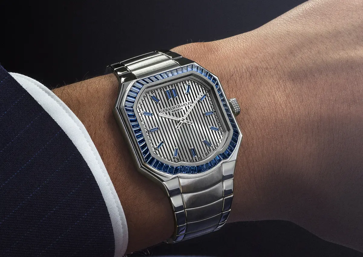 Luksuzna ura Gerald Charles Masterlink Gem-Set z modrimi dragimi kamni na zapestju moškega v elegantni obleki.