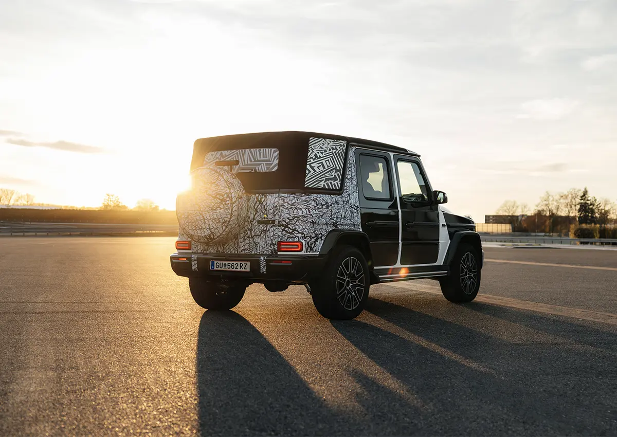 Prototip Mercedes-Benz G-Class Cabriolet v kamuflaži na testni stezi ob sončnem zahodu.