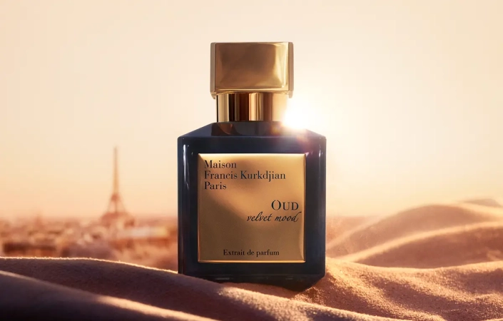 Temna steklenička parfuma Maison Francis Kurkdjian Oud velvet mood z zlatim pokrovčkom na žametni tkanini.
